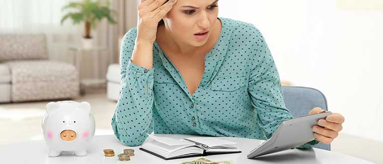 Emotional woman counting taxes at table indoors