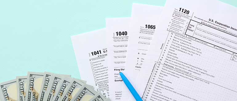 Tax forms lies near hundred dollar bills